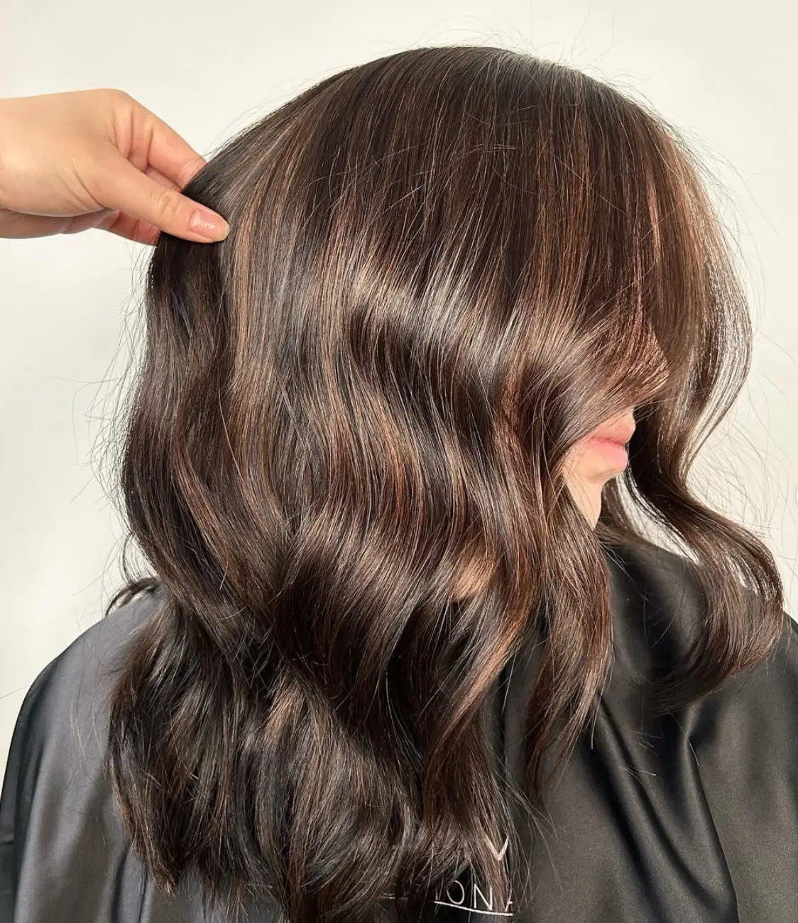 Rich chocolate brunette with subtle copper dimension and soft waves